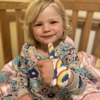Little girl wearing a rainbow thumb guard