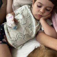 Little girl asleep wearing a Thumbsie ballerina finger guard