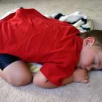 Little boy asleep on the floor whilst thumb sucking