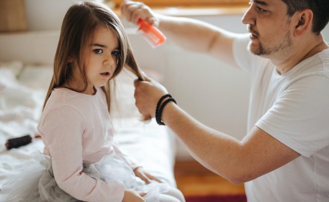 Father brushing his little daughter's hair