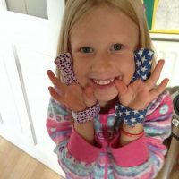 Little girl happily wearing finger guards to stop finger sucking