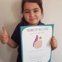 Girl proudly showing off her thumb sucking certificate from Thumbsie